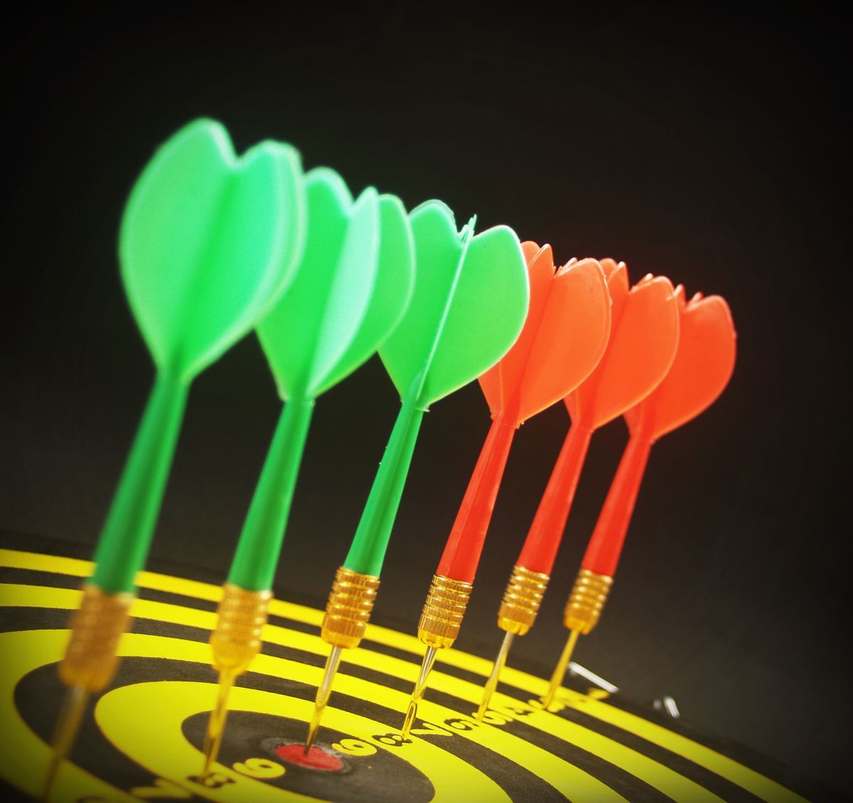 Dartpfeile mit bunten Flights auf der Scheibe