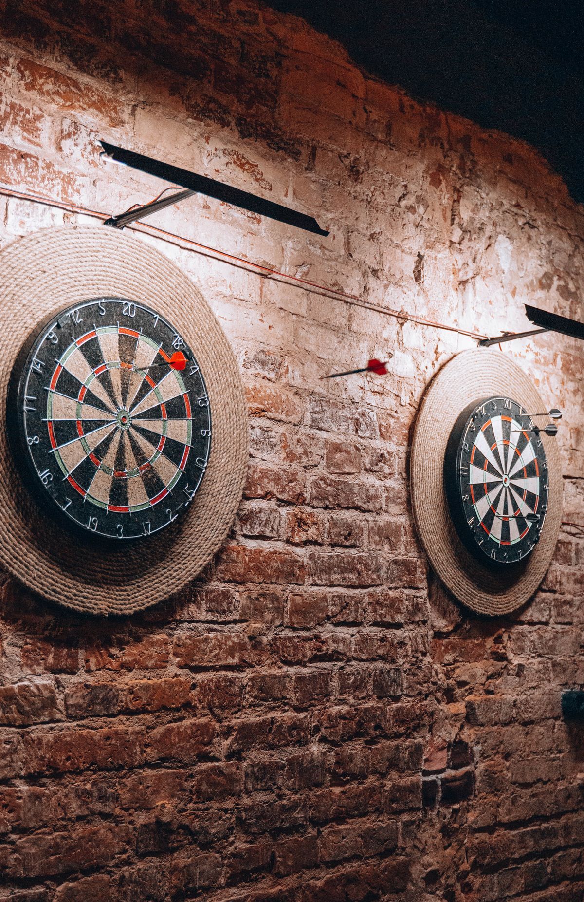Zwei Dartscheiben an einer Backsteinwand
